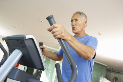 Senior Man On Cross Trainer In Gym