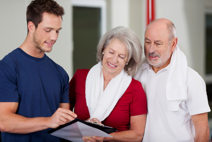 Instructor Showing Health Results On Clipboard To Senior Couple