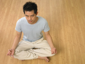 man doing yoga at home with eye closed