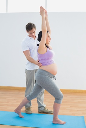 Pregnant woman doing yoga with a personal trainer