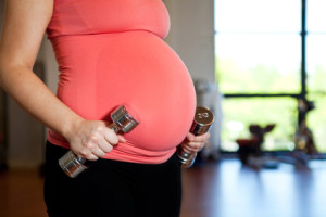 Pregnant woman holding dumbbells