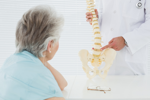 Male doctor explaining the spine to a senior patient in medical office