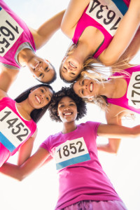 Portrait of five smiling runners supporting breast cancer marathon in parkland