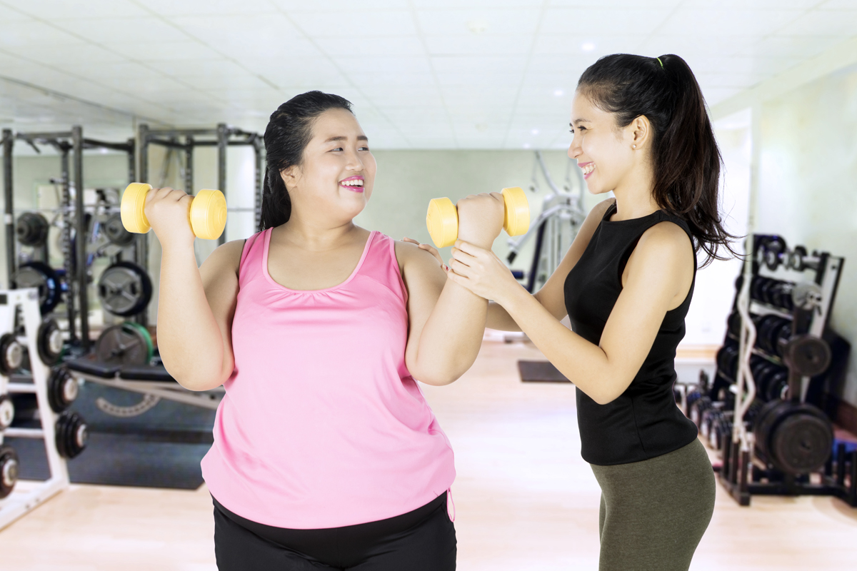 Personal trainer and her client with dumbbells