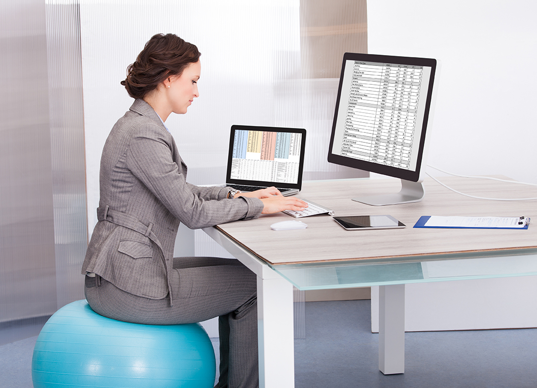 Woman Sitting On Pilates Ball Using Computer